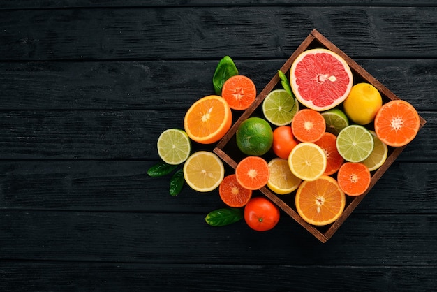 Assorted citrus fruit in a wooden box Orange tangerine grapefruit lemon On a wooden background Top view Copy space