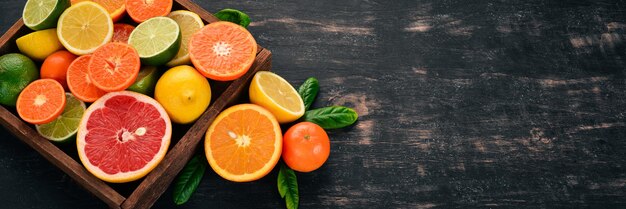 Assorted citrus fruit in a wooden box Orange tangerine grapefruit lemon On a wooden background Top view Copy space