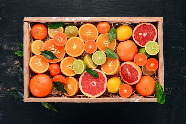 Assorted citrus fruit in a wooden box Orange tangerine grapefruit lemon On a wooden background Top view Copy space