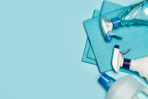 Assorted cleaning products bottles on a light blue background