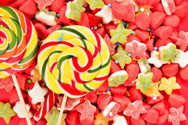Ассорти красочных желейных конфет и леденцов на красном фоне вид сверху желейные сладости