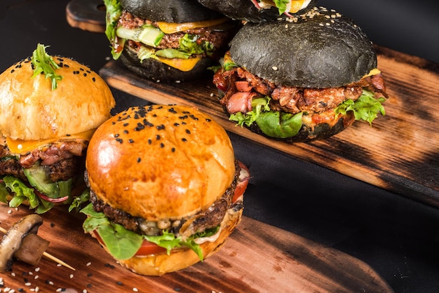 Assorted craft burgers with different fillings, with sesame seeds on the black background