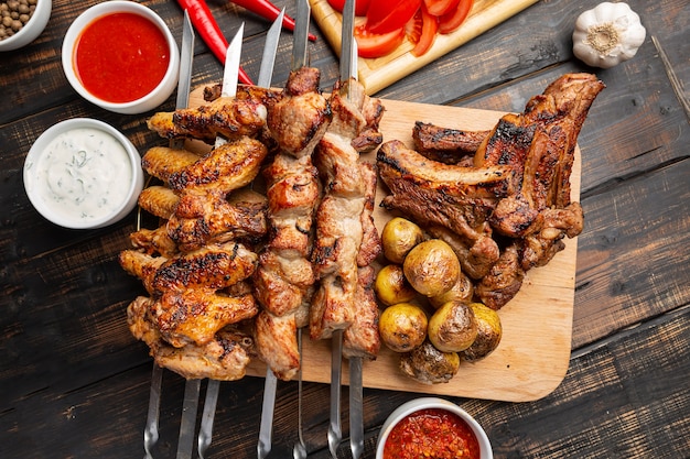 Deliziosa carne alla griglia assortita su spiedini con verdure fresche e patate al forno vista dall'alto