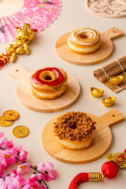 写真 各種ドーナツまたは木製トレイのドーナツプレートとクリーム色の背景と中国の装飾品で撮影