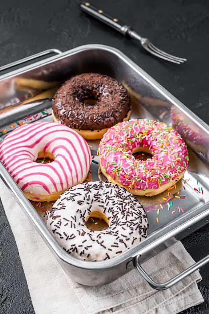 Assorted donuts with chocolate, pink glazed and sprinkles Doughnut. Black background. Top view.