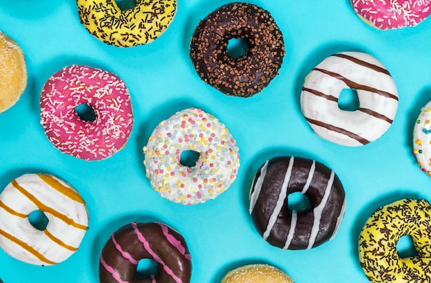 Assorted donuts with different fillings and icing on a blue back