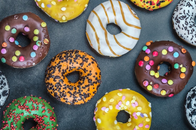 Assorted donuts with icing and feelings on a black background. Background of assorted doughnuts with different flavors