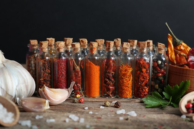 Assorted dry spices in glass bottles on dark background