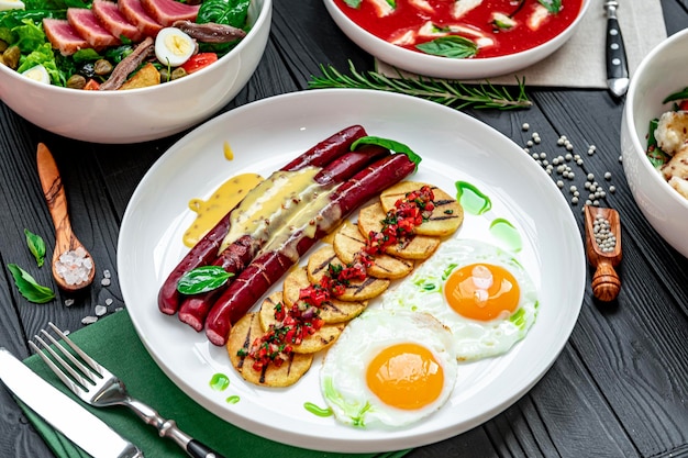 Фото Различная еда на столе томатный суп с моцареллой, салат из тунца, яичница с колбасыми, различные блюда в ресторане