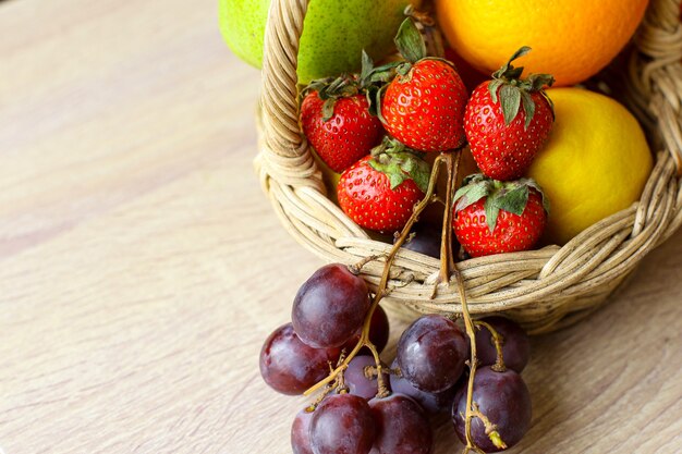Assorted fresh fruits in basket on wooden table