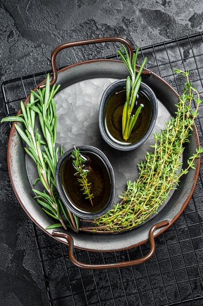 Assorted fresh herbs with olive oil Top view Dark background