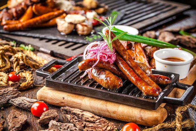 Salsiccie fritte assortite su una griglia su un bordo di legno.