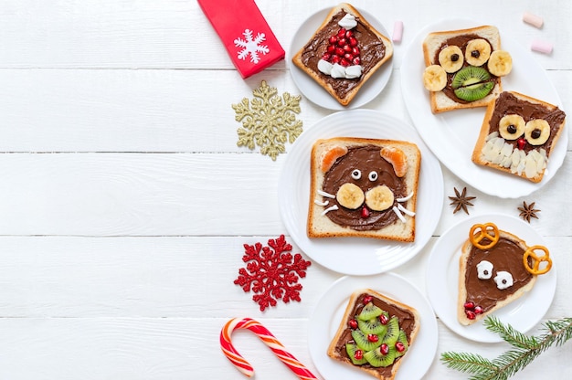 Assorted funny sandwiches with chocolate, fresh fruit, marshmallows on plates, top view. The idea of a menu for a children's party. Creative breakfast, Christmas theme. Copy space