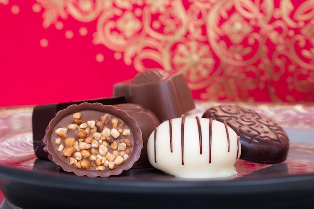 Assorted gourmet chocolate candies in different shapes and colors in the dish.