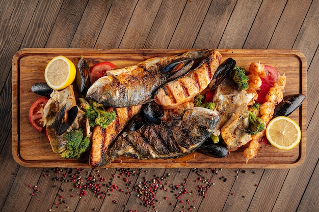 Assorted grilled fish set on wooden serving board