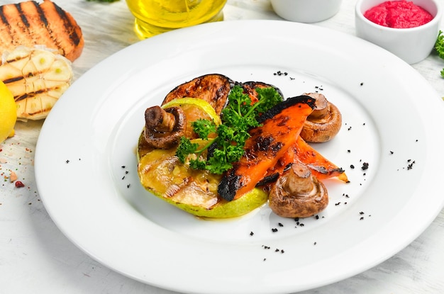 Assorted grilled vegetables: mushrooms, peppers, paprika, zucchini and eggplant on a plate. Top view.