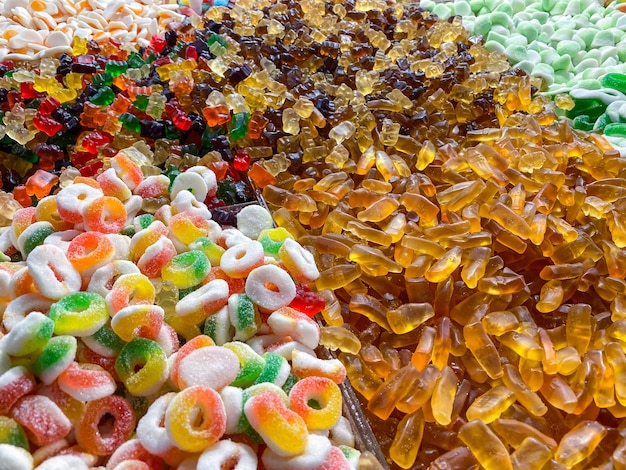Caramelle gommose assortite e gelatine come sfondo. un sacco di caramelle colorate al gusto di caramelle. vista dall'alto.