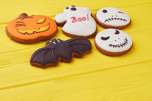 Photo assorted halloween biscuits on yellow background various gingerbread cookies with icing for hallowee...