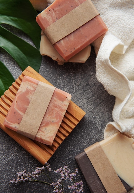 Assorted handmade soap bars towels and green leaves on concrete background