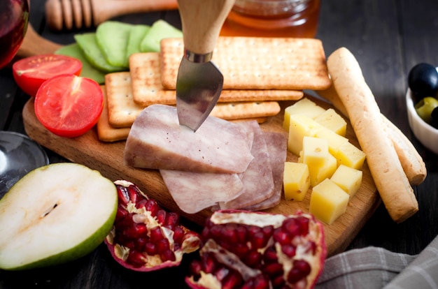 Assorted homemade pieces cheese with honey, fruits, cookies and nuts on table.  Fresh dairy product, healthy organic food. Delicious appetizer.