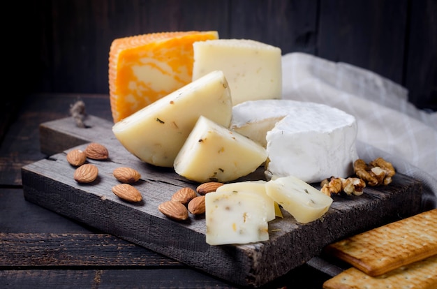 Assorted homemade pieces cheese with honey, fruits, cookies and nuts on table