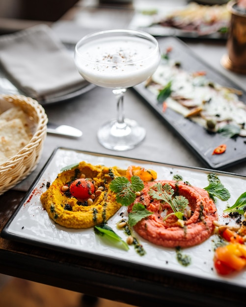 Assorted hummus dip with sour foam cocktail on the served restaurant table