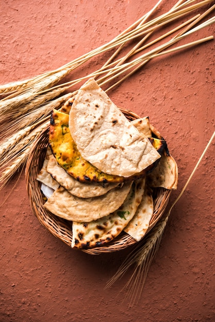 Фото Ассорти из индийской корзины для хлеба включает чапати, тандури роти или наан, паратха, кульча, фулку, мисси роти.