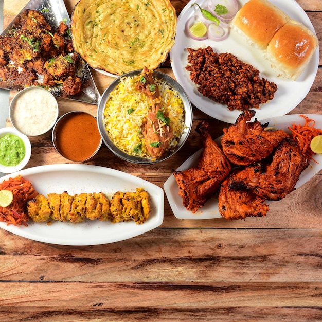 Assorted indian food on wooden background chicken tikka chicken\
briyani tandoori chicken masala kulcha dishes and appetizers of\
indian cuisine