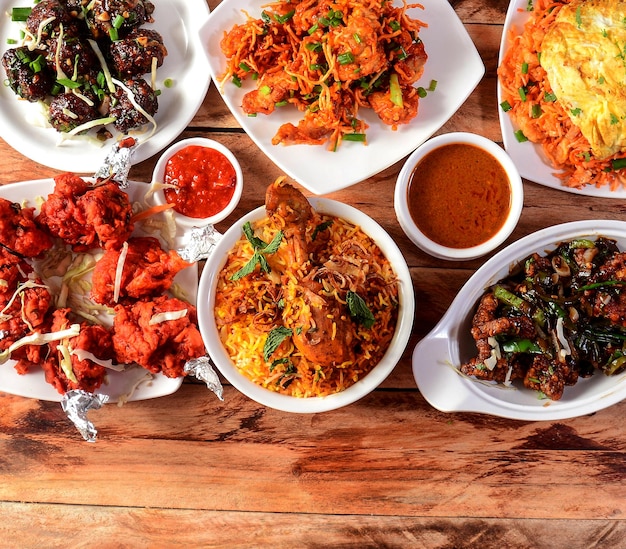 Photo assorted indian foods chicken biryanichicken lollipoppepper chicken and pepper gobi on wooden background dishes and appetizers of indian cuisine