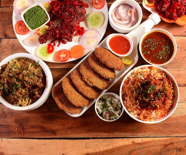 Assorted indian foods chicken biryanimutton biryanitandoori\
chicken and chicken russian kebab on wooden background dishes and\
appetizers of indian cuisine