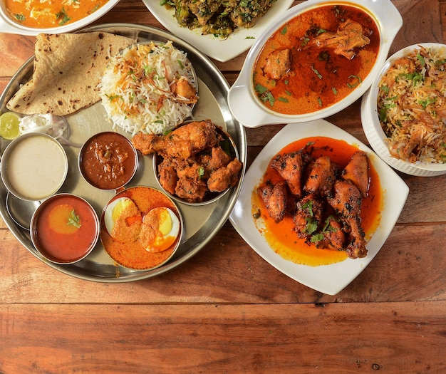 Assorted indian foods pepper chicken gravychicken masala and\
nonveg thali on wooden background dishes and appetizers of indian\
cuisine