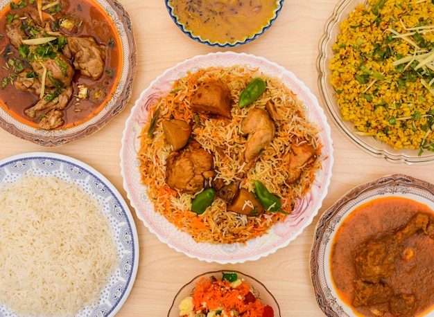 모듬된 인도 매운 음식 치킨 비리야니 치킨 니하리 달 차왈 다알 마쉬 자르다 또는 조르다 쌀이 탁자 위에서 분리된 접시에 담겨 제공됩니다