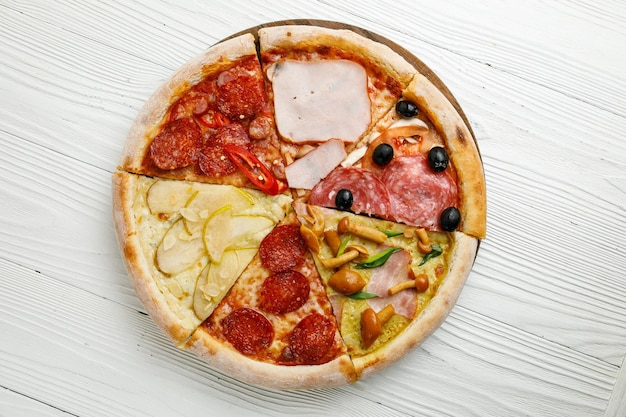 Assorted Italian pizza on a white wooden table Different pieces in one portion set