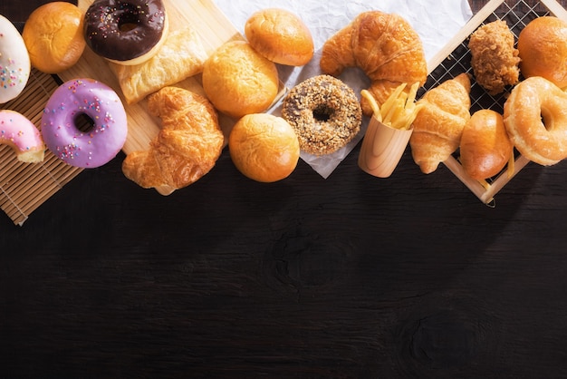 Assorted junk food multiple type on black wooden table of top view with copy space.