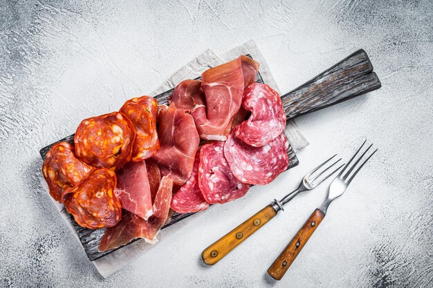 Assorted meat appetizers - salami, jamon, choriso sausages. White background. Top view.