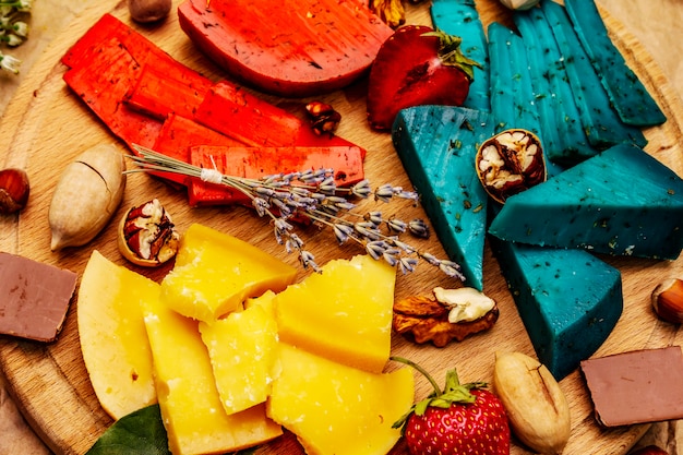 Assorted multi colored hard Dutch cheeses on round wooden cutting board