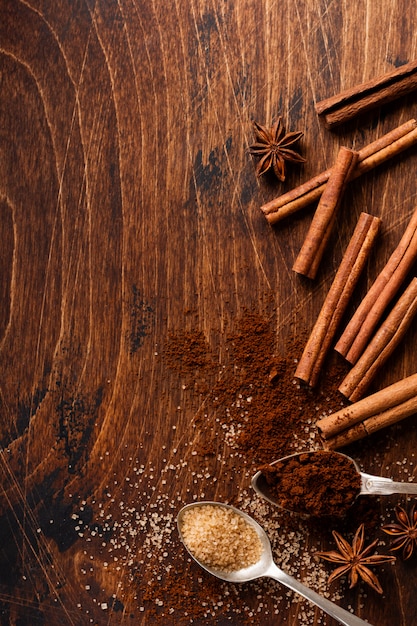 Assorted natural cinnamon, cane brown sugar, anise stars on a rustic brown background