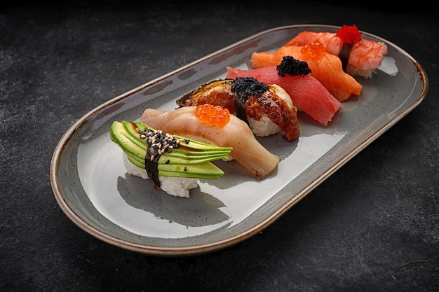 Assorted Nigiri sushi on a plate on dark concrete