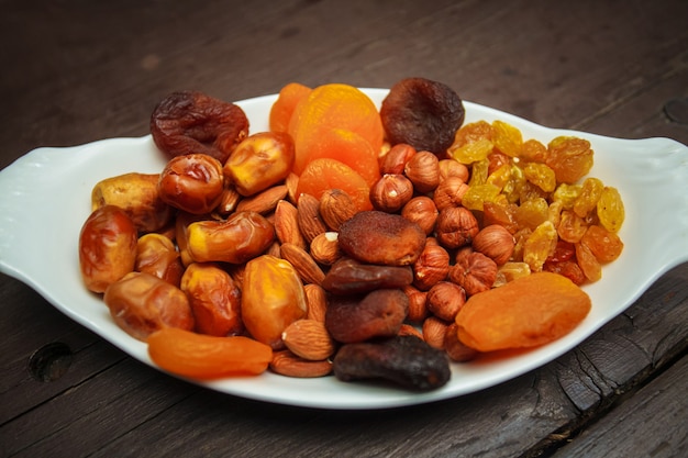 Assorted nuts and dried fruits in white plate.