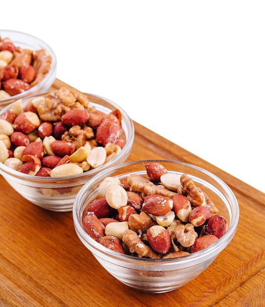 Assorted nuts in a glass bowls on wooden