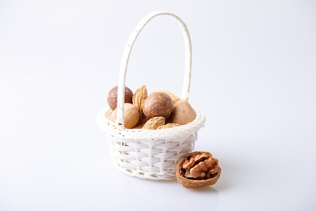Assorted nuts in the shell on a white background walnuts pecans almonds macadamia Nuts in a basket Selective focus closeup Place for text