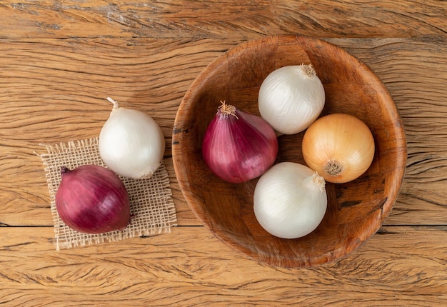 Assorted onions in a bowl over wooden table