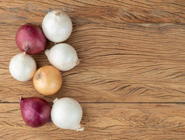 Assorted onions over wooden table with copy space