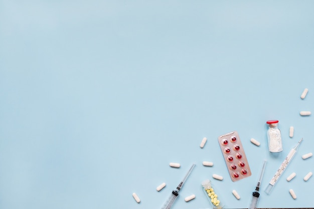 Assorted pharmaceutical medicine pills, tablets and capsules over blue background