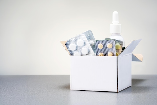 コピー スペースとベージュ色の背景のボックスに医薬品の丸薬の錠剤とカプセルの盛り合わせ