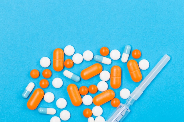 Assorted pharmaceutical medicine pills, tablets and syringe on EU euros on white background. Healthcare concept. Crisis. Money. Free space. Copy space.