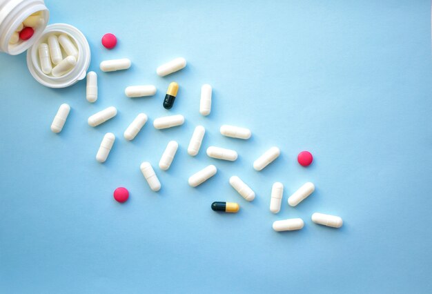 Assorted pharmaceutical tablets and capsules pouring out of a bottle