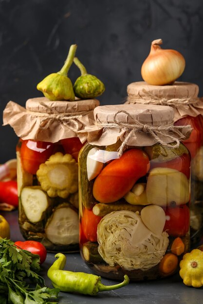 Photo assorted pickled cucumbers, patissons, tomatoes, carrots, zucchini, cabbage and pepper in jars