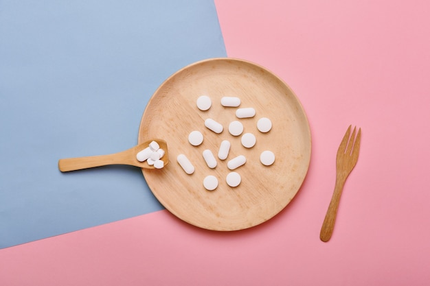 Assorted pills on a wooden plate and spoon