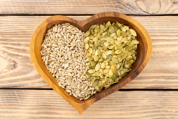 Assorted pumpkin and sunflower seeds in a heart shaped wooden plate